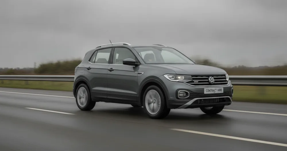Small SUV driving along an overcast UK motorway, showing a volkswagen t-cross lease choice. Small SUV driving along an overcast UK motorway, showing a volkswagen t-cross lease choice.